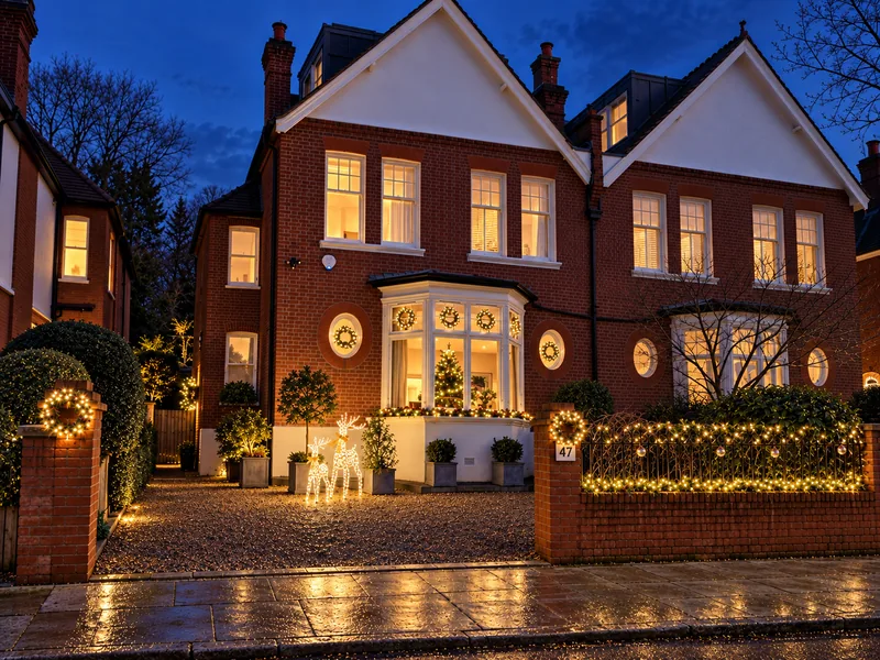 The same Putney house at blue hour with warm white lights around the bay, entrance and front garden