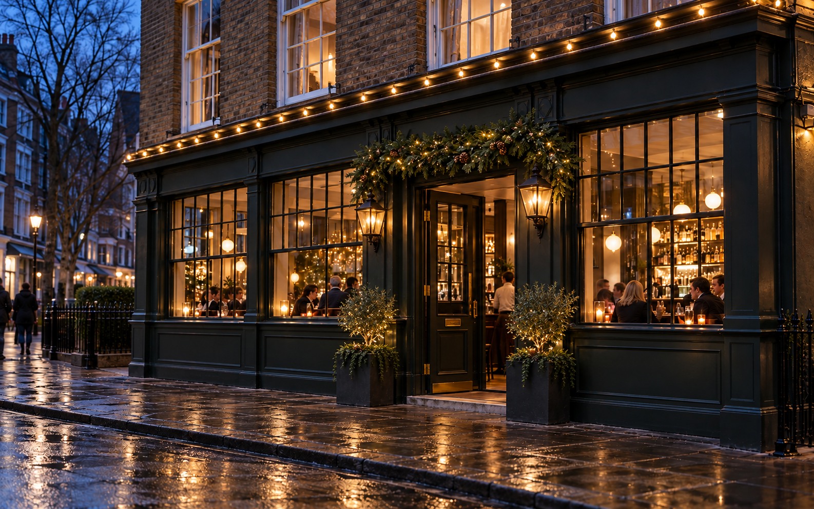 Dark-painted restaurant frontage with warm white roofline lights, entrance greenery and glowing windows