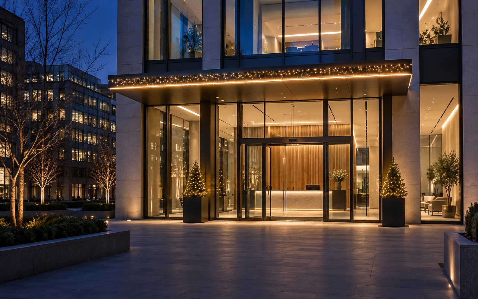 Contemporary glass office reception with warm white canopy lighting and entrance planters